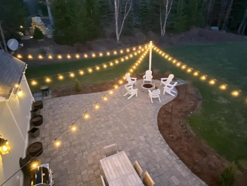 Bistro string lights hung in radial rows over an outdoor fire pit patio