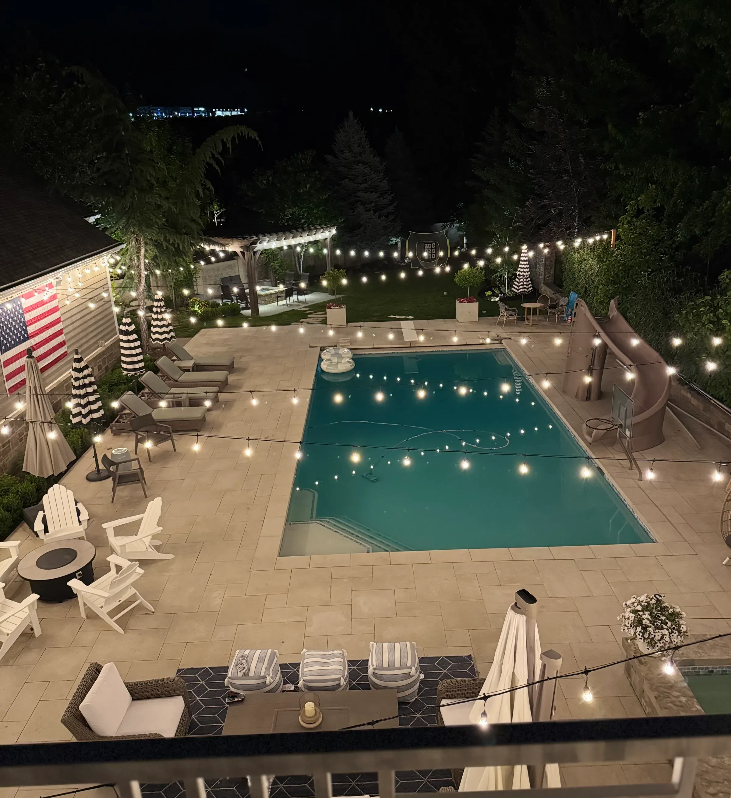Bistro string light canopy over an expansive swimming pool and patio