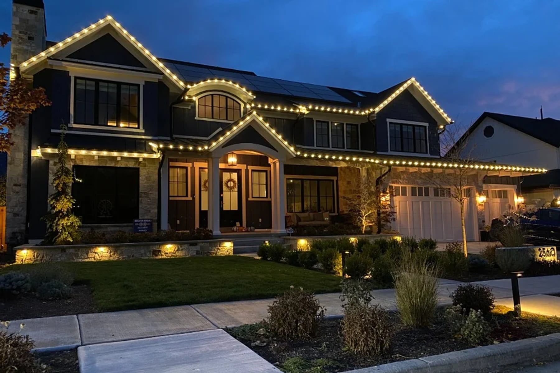 Custom holiday roofline and architectural lighting on a Utah home at dusk