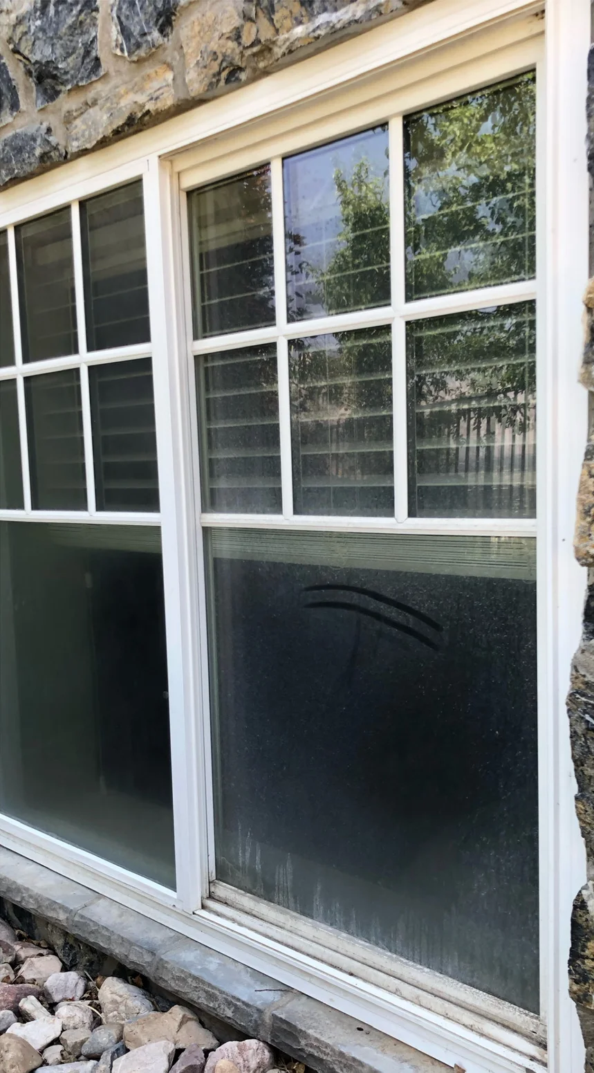 White-framed windows in a stone wall before cleaning