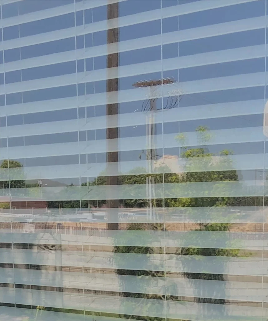 Window glass with white blinds behind it before cleaning