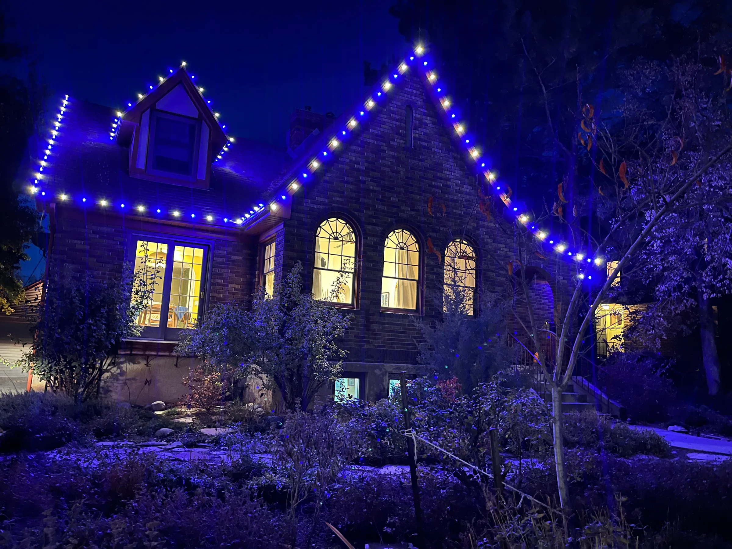 Stone Tudor home outlined in blue and white lights
