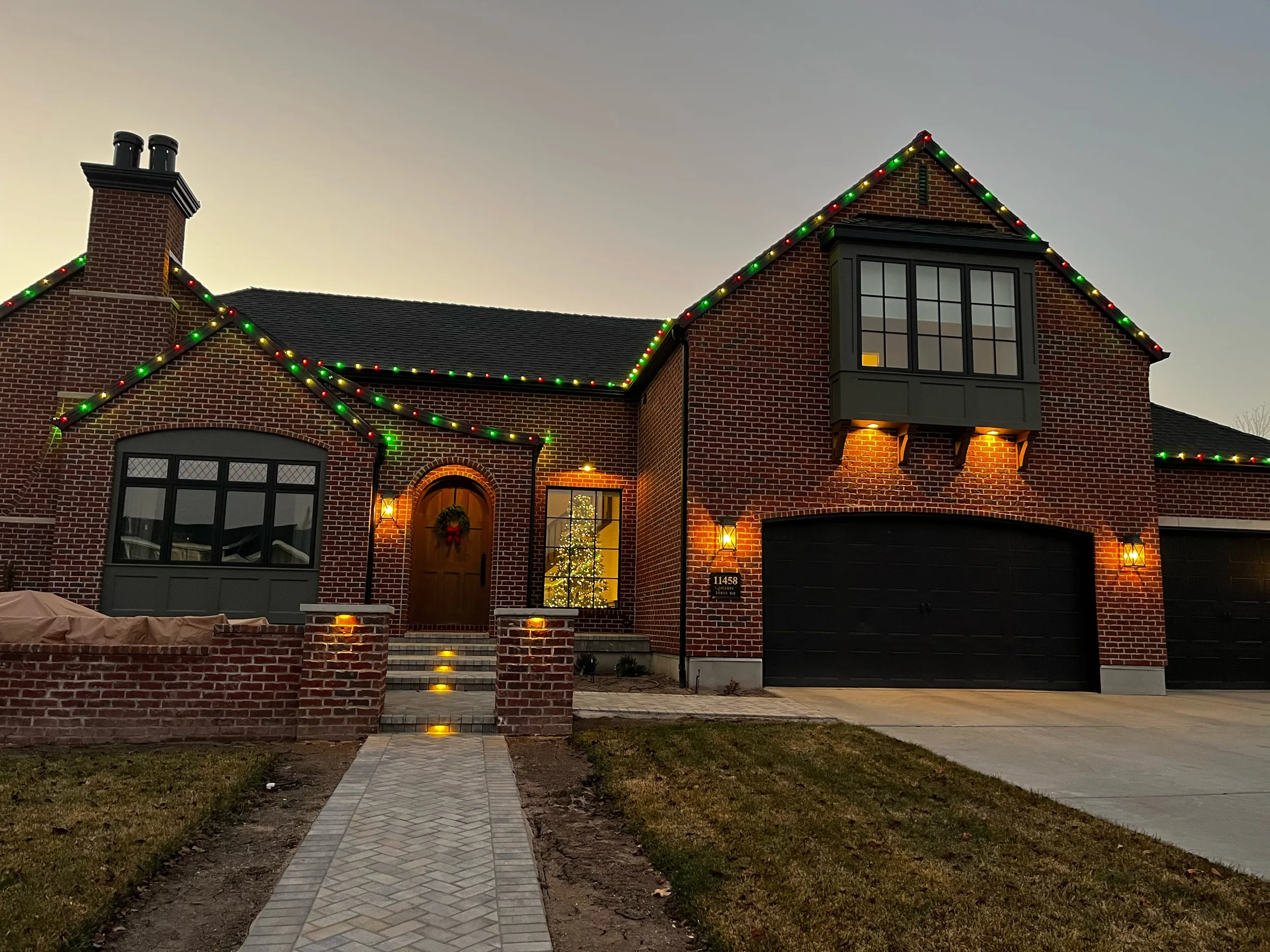 Brick home with green roofline lights at dusk