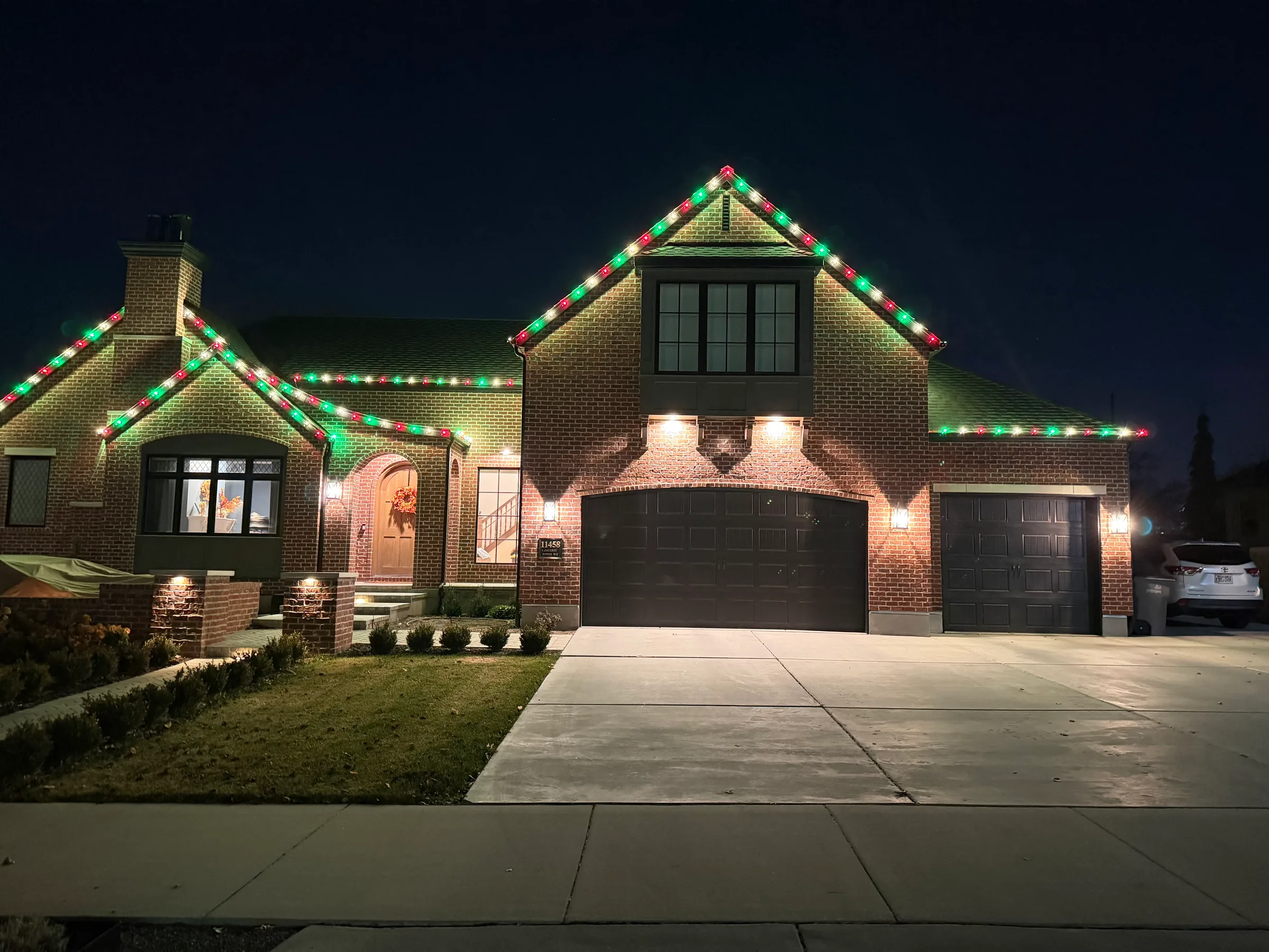 Brick home with green and red roofline lights at night