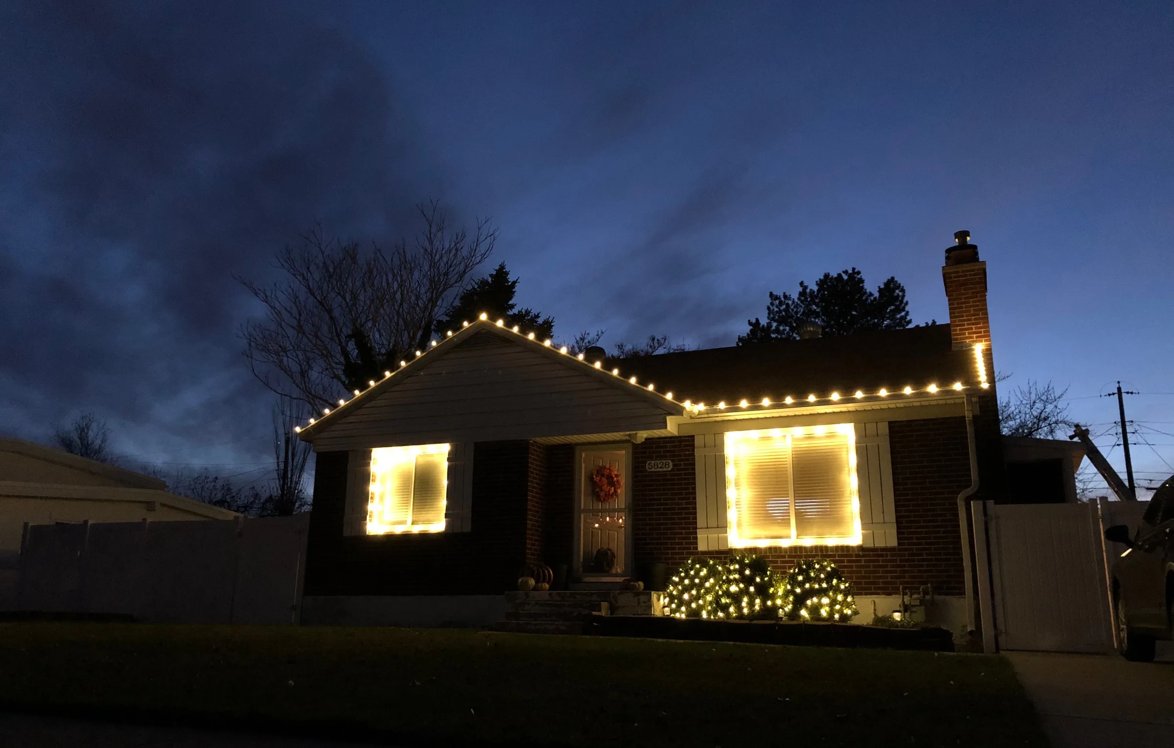 Brick home with lit rooflines and framed windows