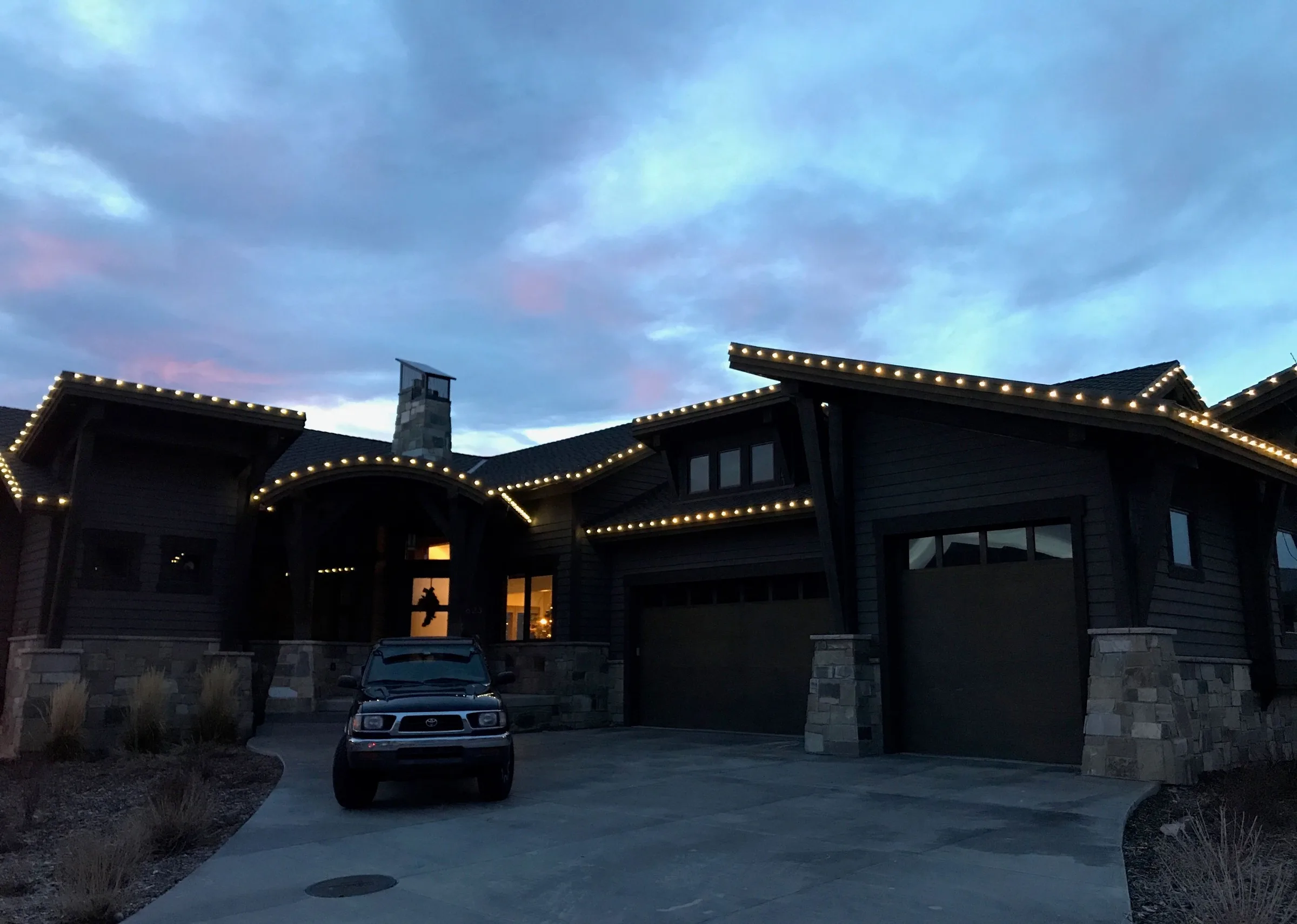 Craftsman home with warm roofline lights at dusk