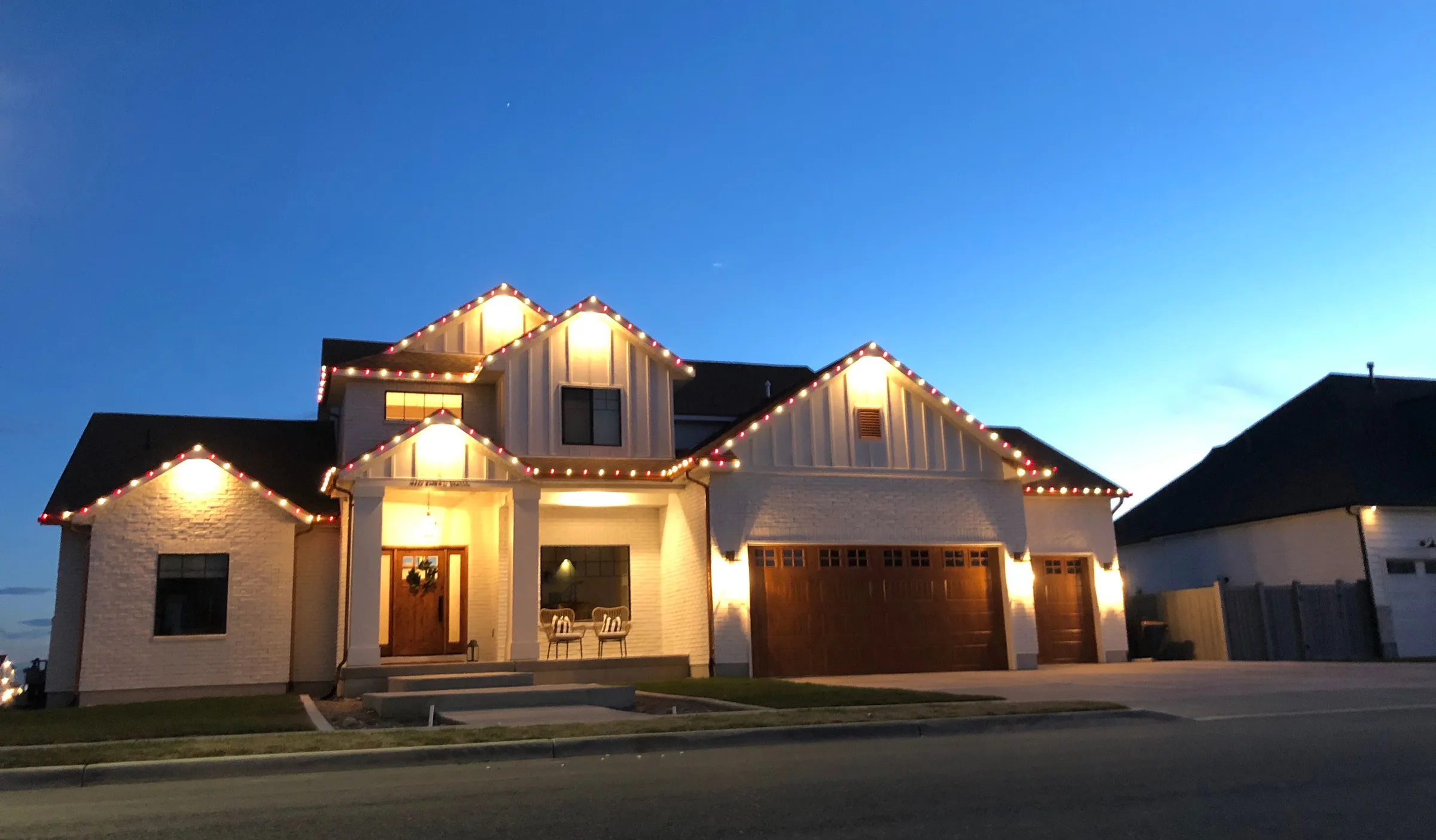 White farmhouse with red and white rooflines at blue hour