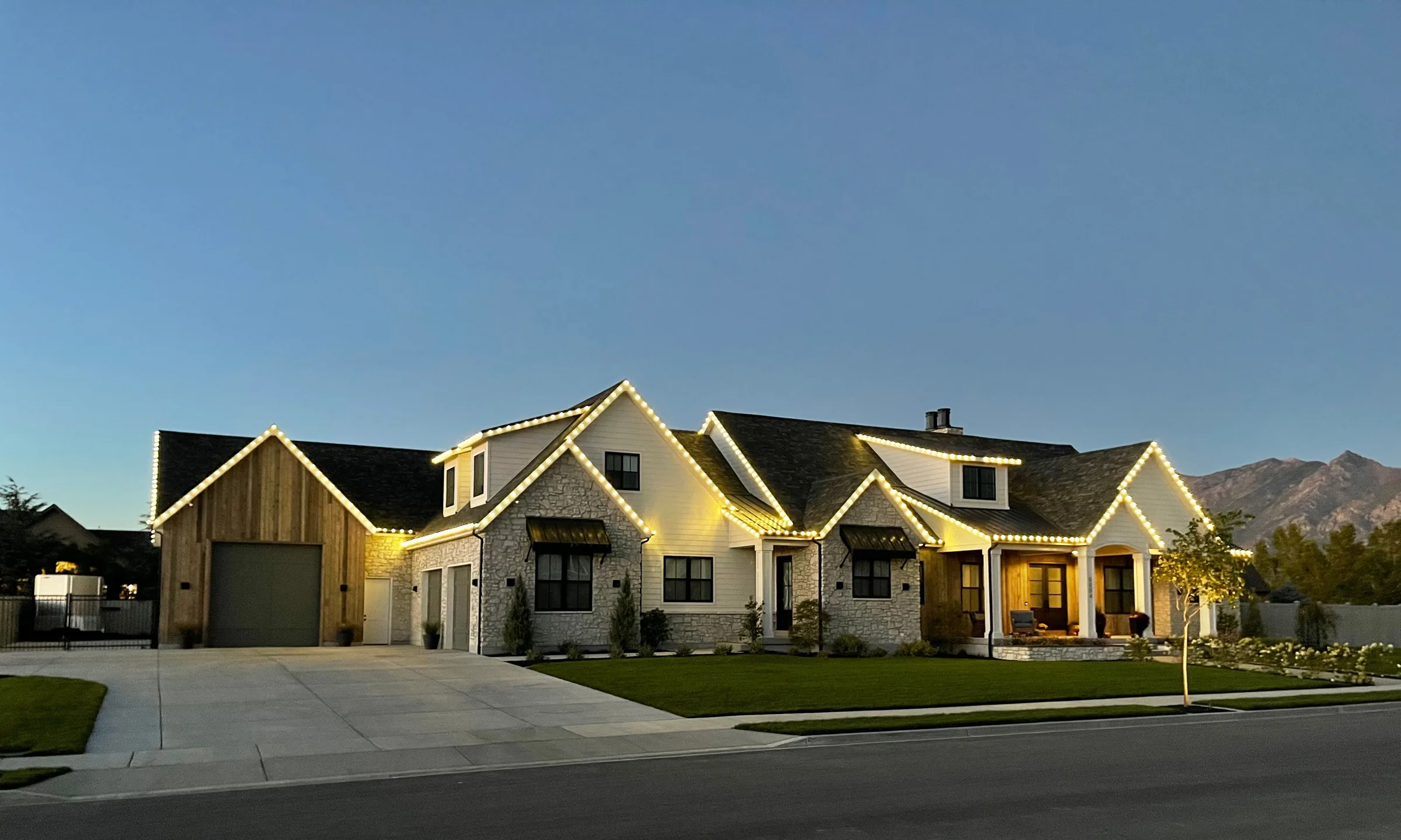 Farmhouse rooflines lit warm white with mountains behind