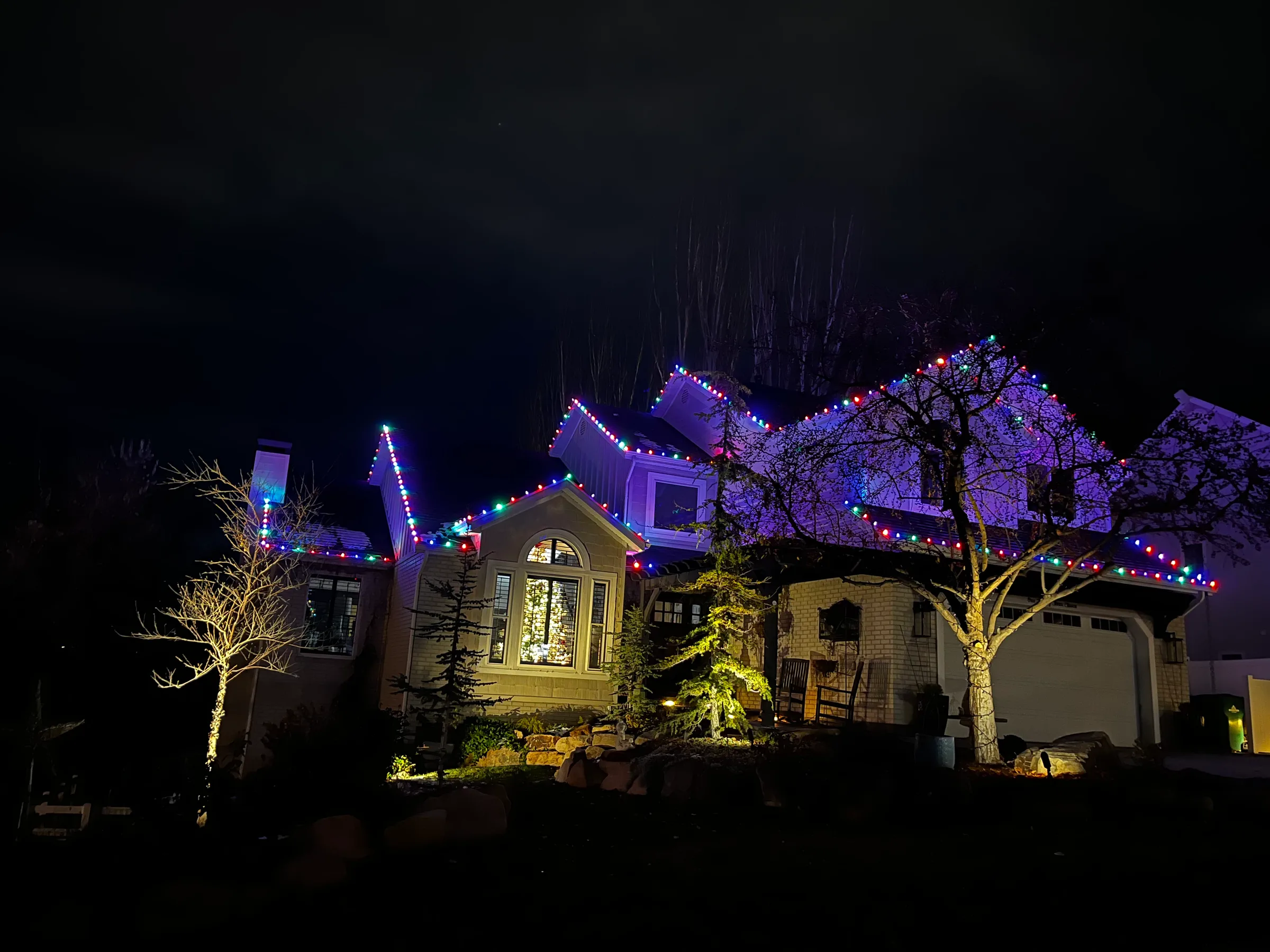 Hillside home with multicolour rooflines and lit trees