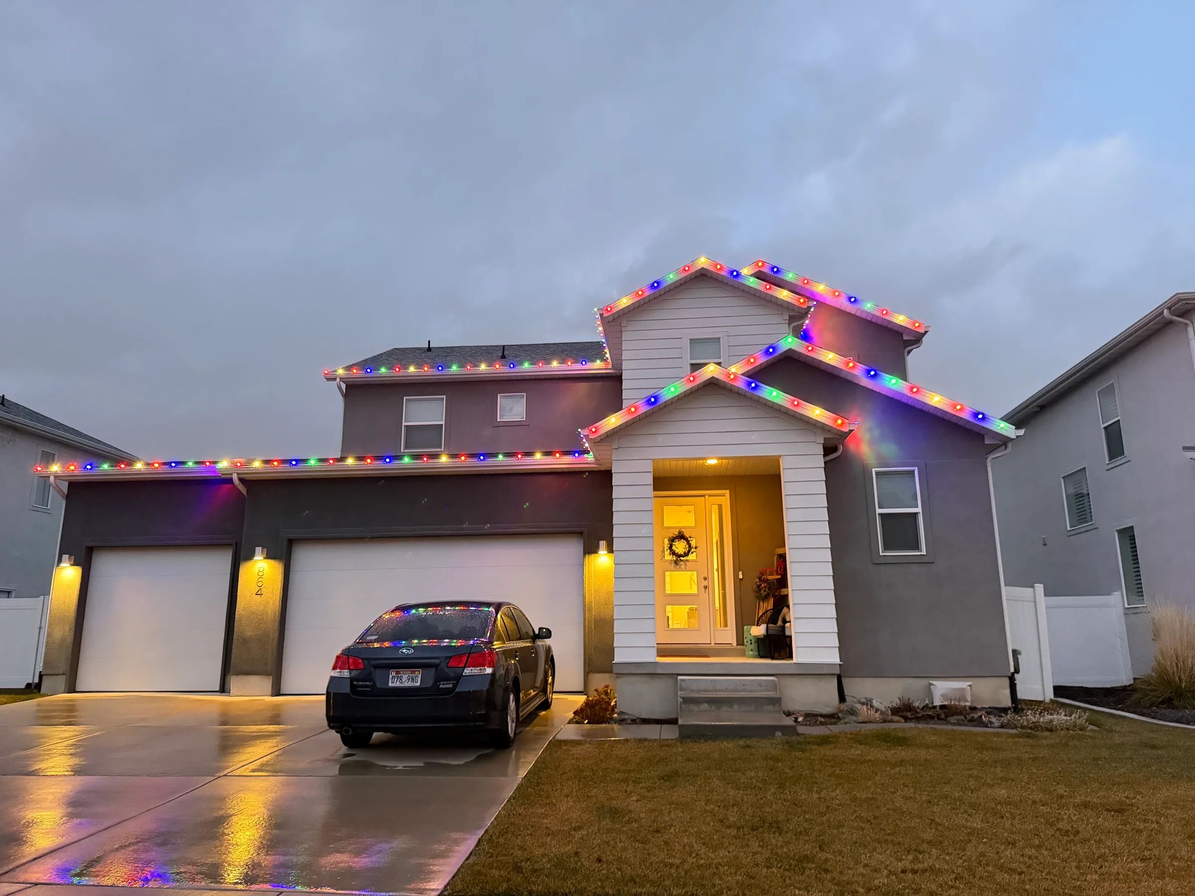 Two-story home outlined in multicolour lights after an evening rain