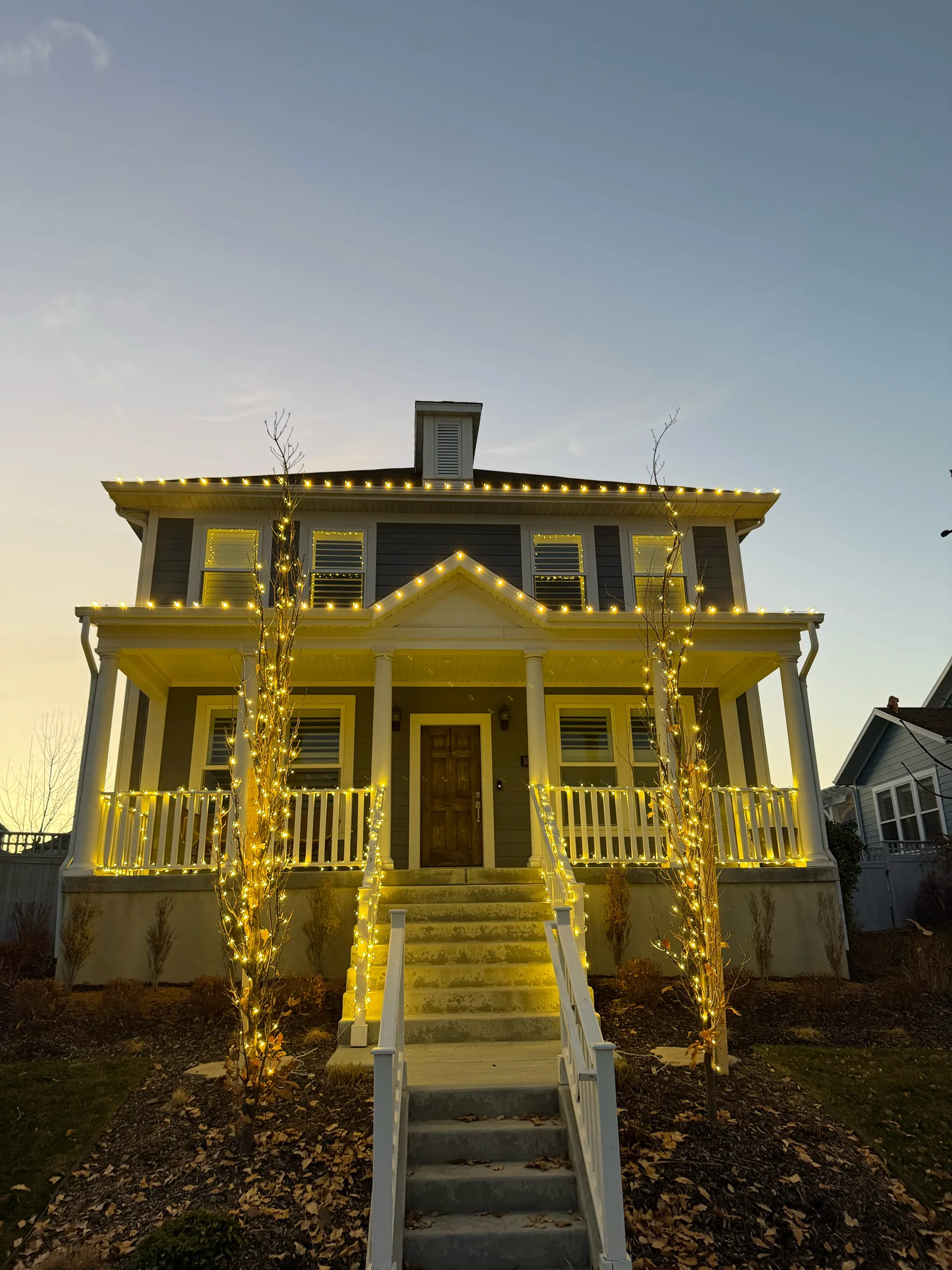 Wraparound porch with columns and rooflines lit