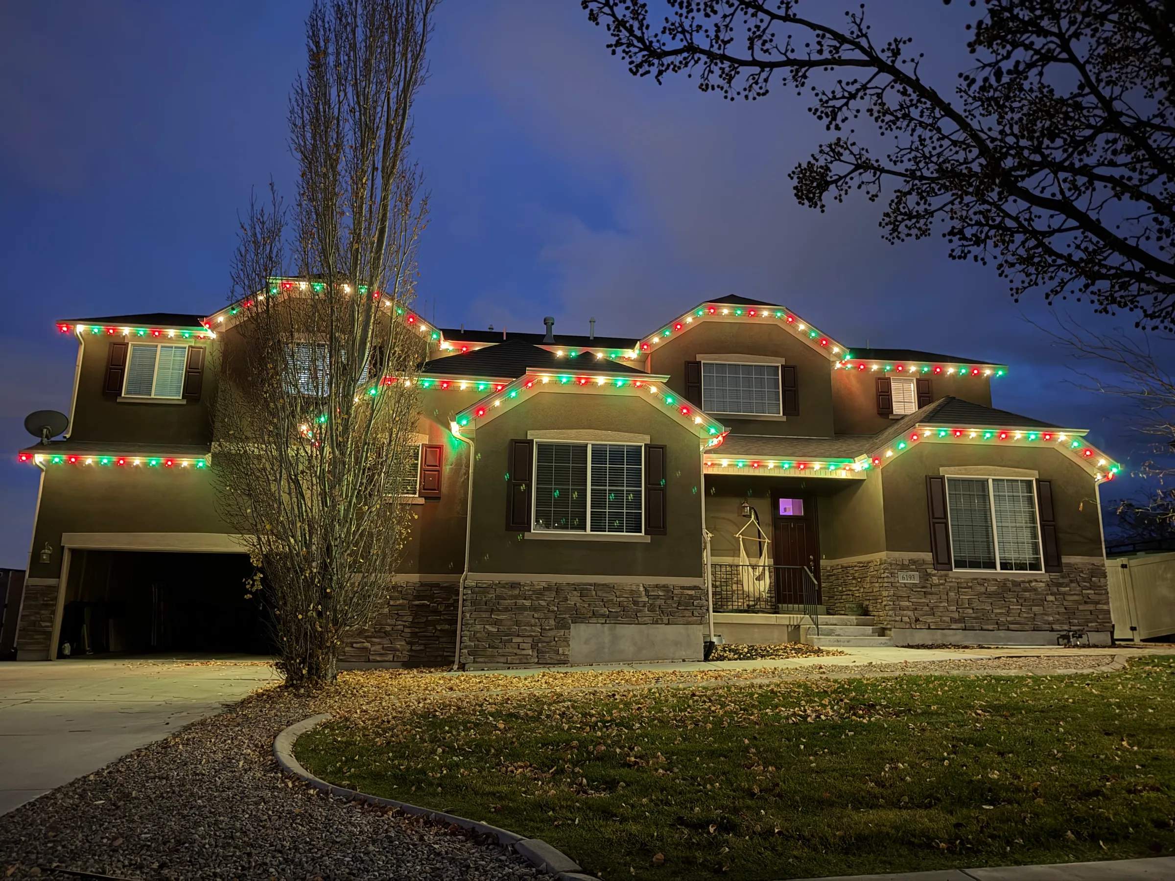 Stucco home with red, green and white rooflines at dusk