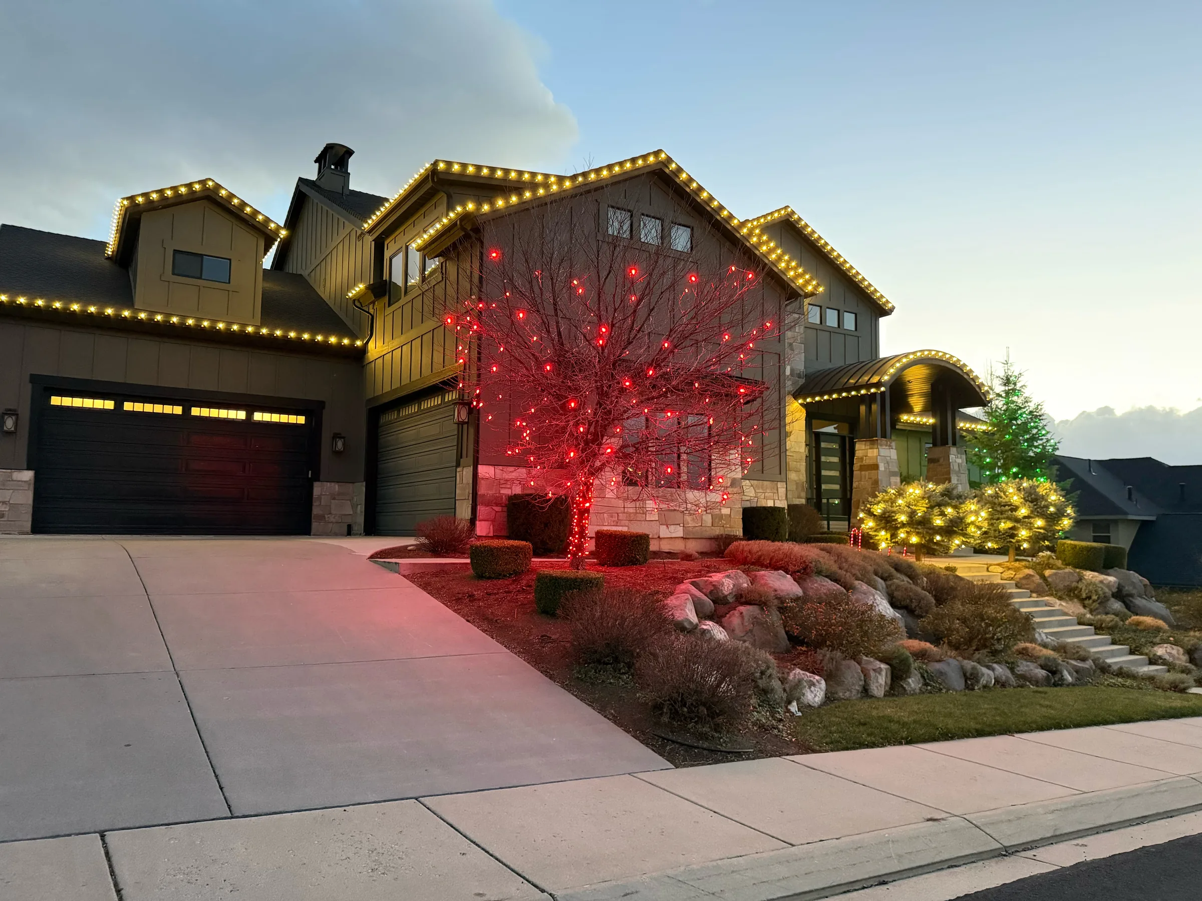 Warm roofline lights with red and green wrapped trees