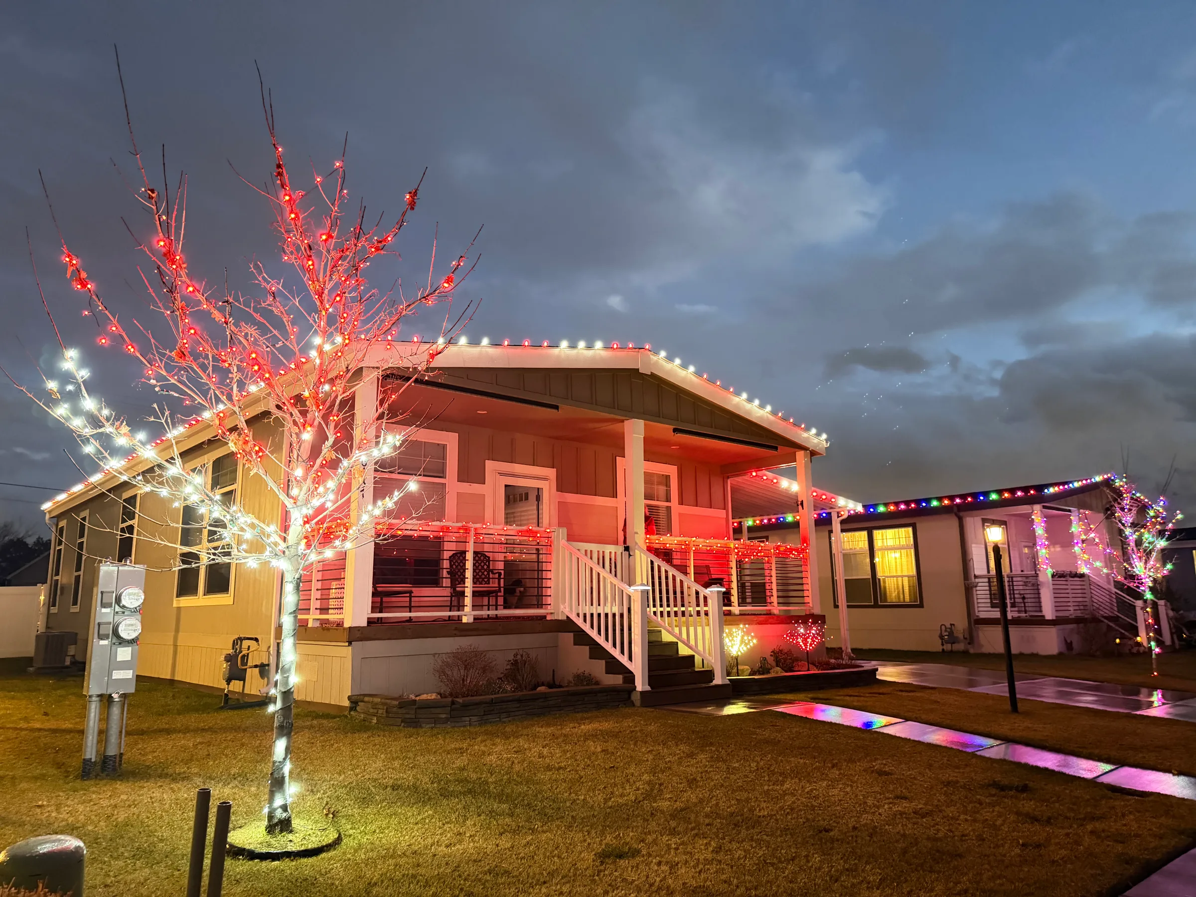 Two-story home with red and white rooflines and an illuminated tree