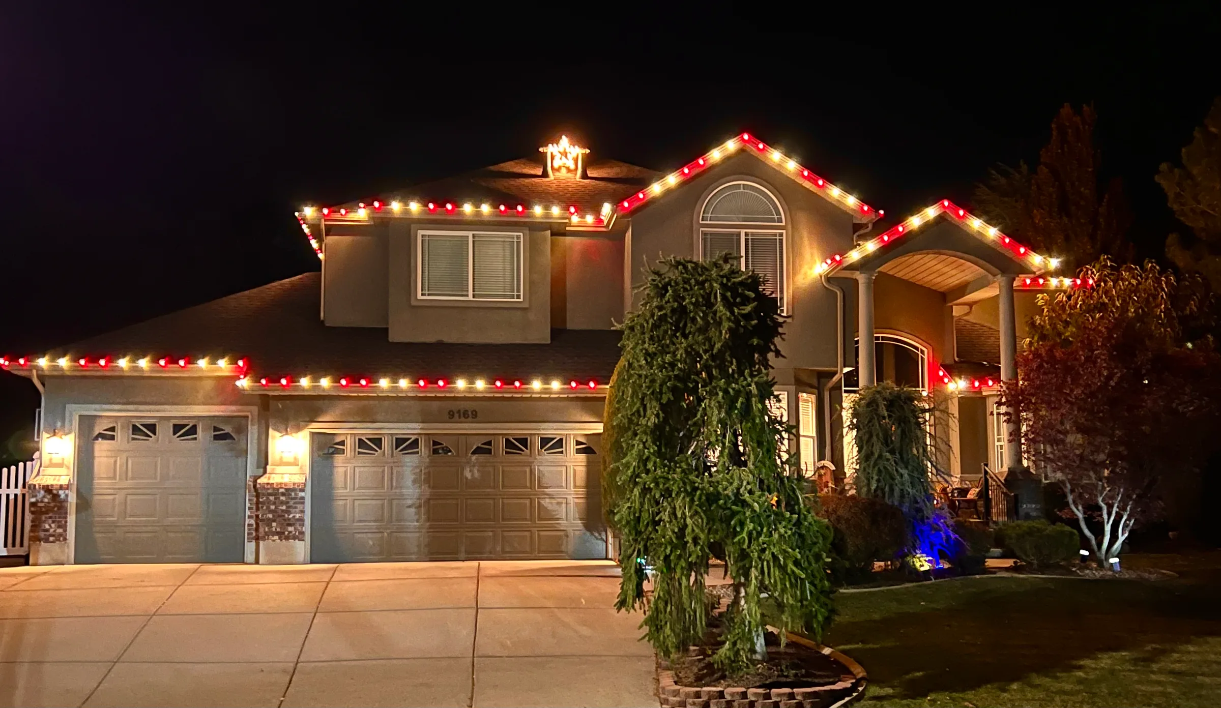 Two-story home with red and warm white rooflines and a lit star