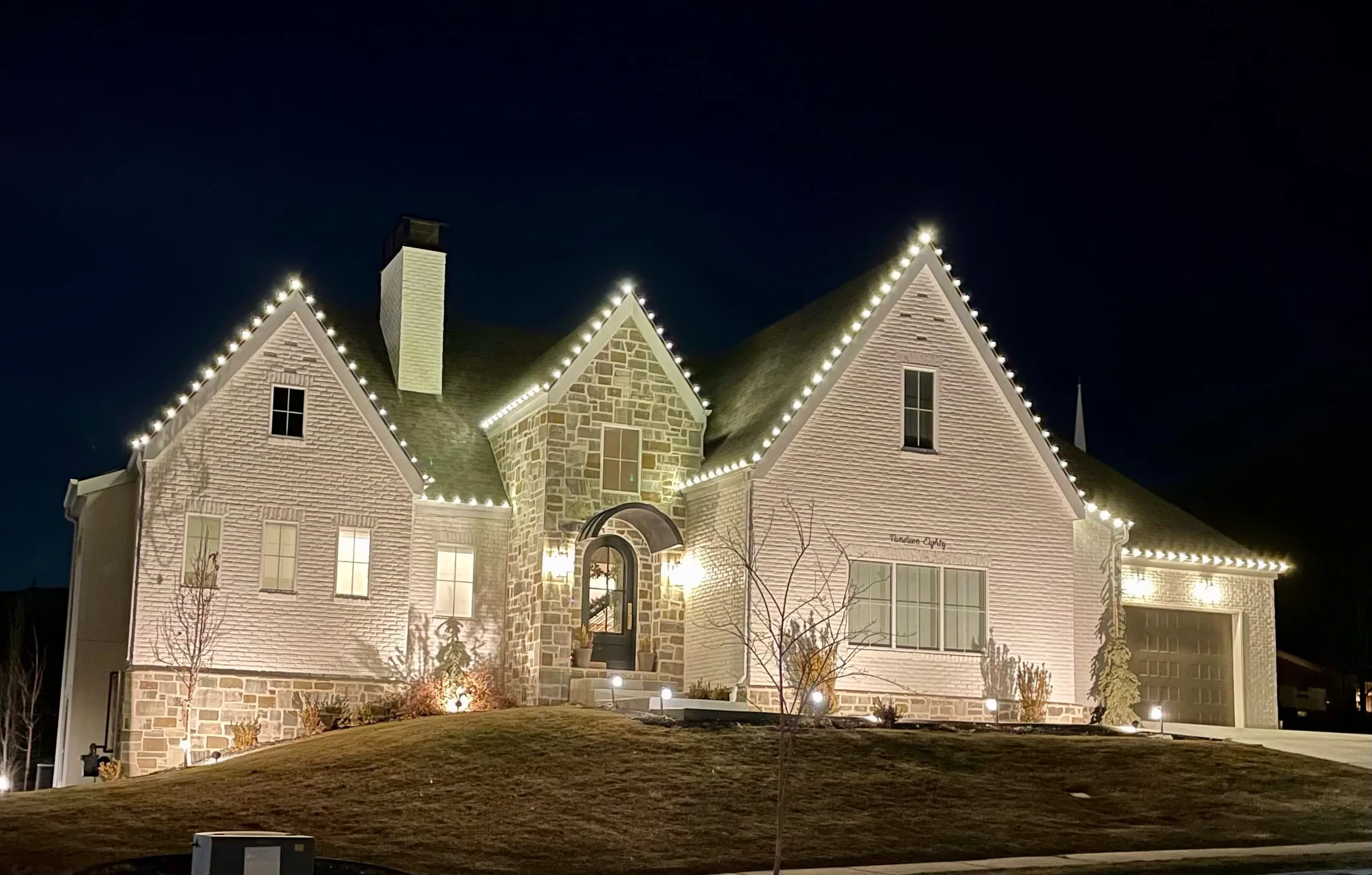 Stone cottage with steep gables lit in warm white