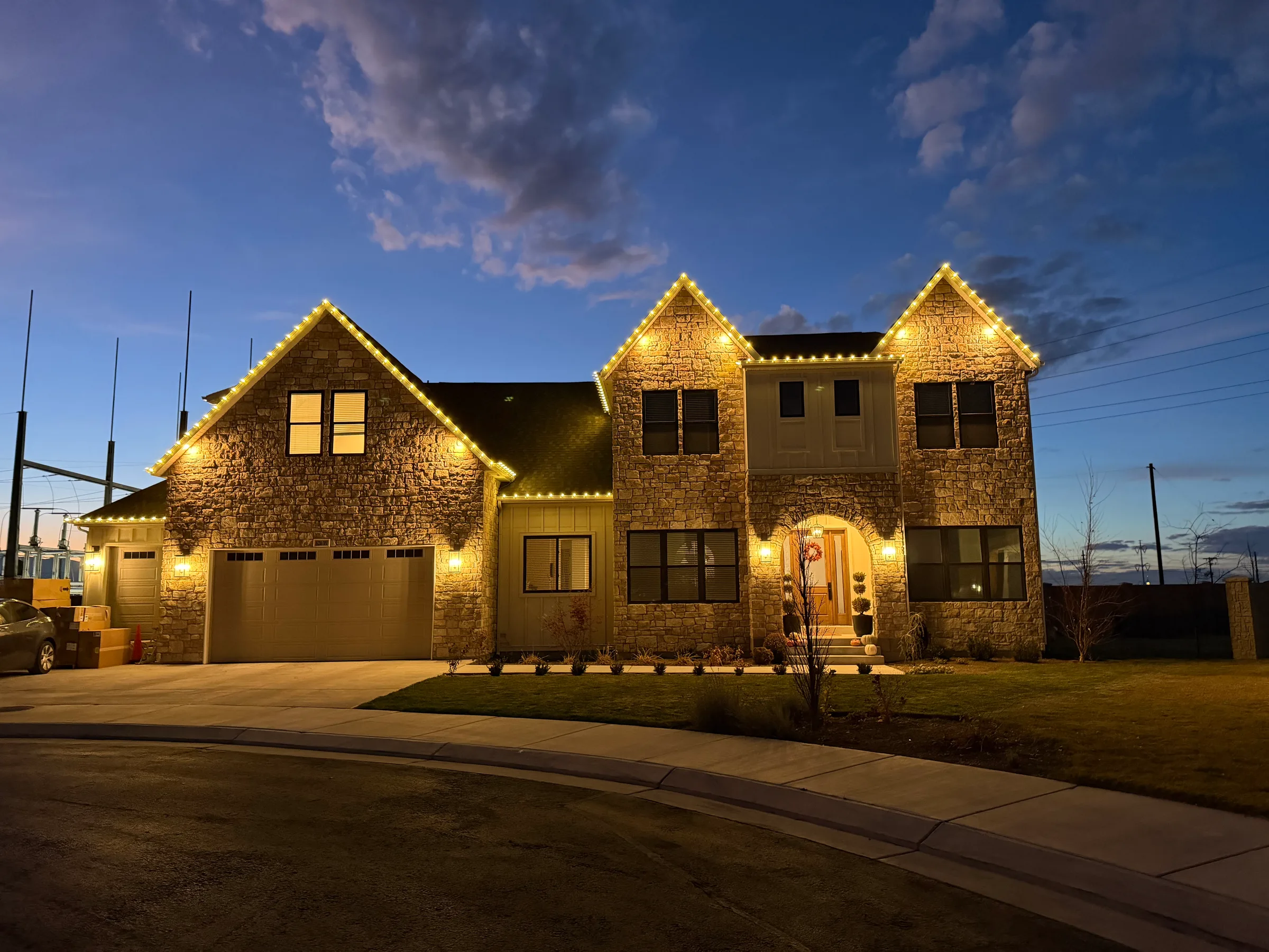 Stone home with three gables in warm white at dusk