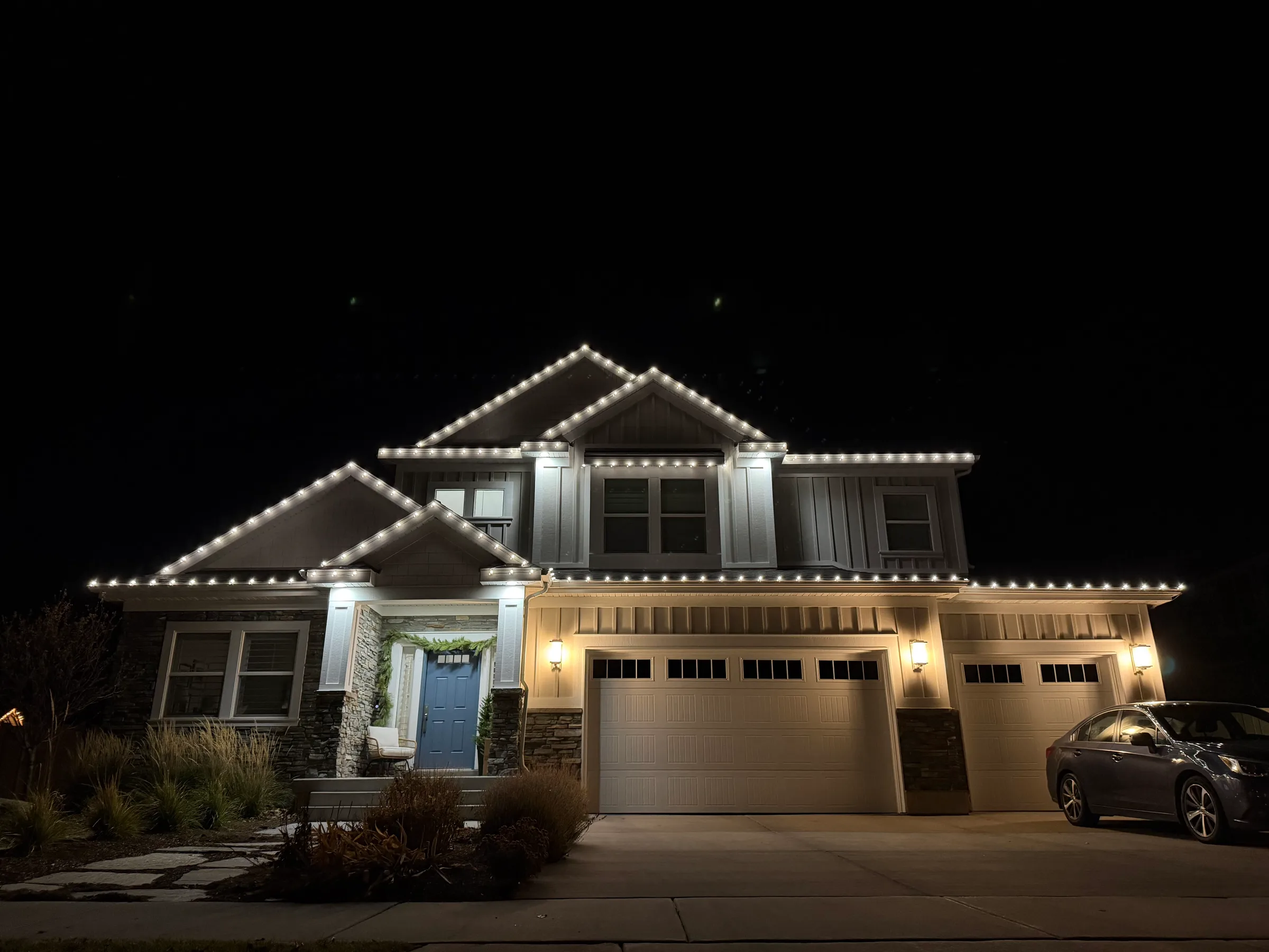 Two-story home outlined in white over a three-car garage